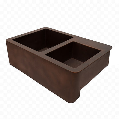 Angled view of a custom apron copper kitchen sink with large left and smaller right bowl