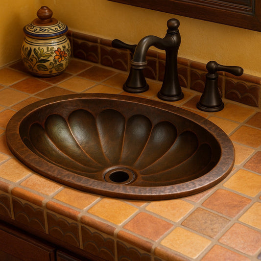 Custom oval copper drop In or undermount sink with spiral scalloped basin in a bathroom with ceramic tile counter and bronze faucet