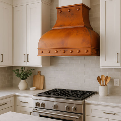 Distressed copper range hood with dome body and rivet accents in a transitional kitchen design