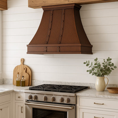 Hammered copper range hood with vertical riveted straps in a rustic farmhouse style kitchen
