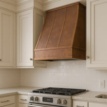 Rectangular sloped copper range hood in a transitional style kitchen